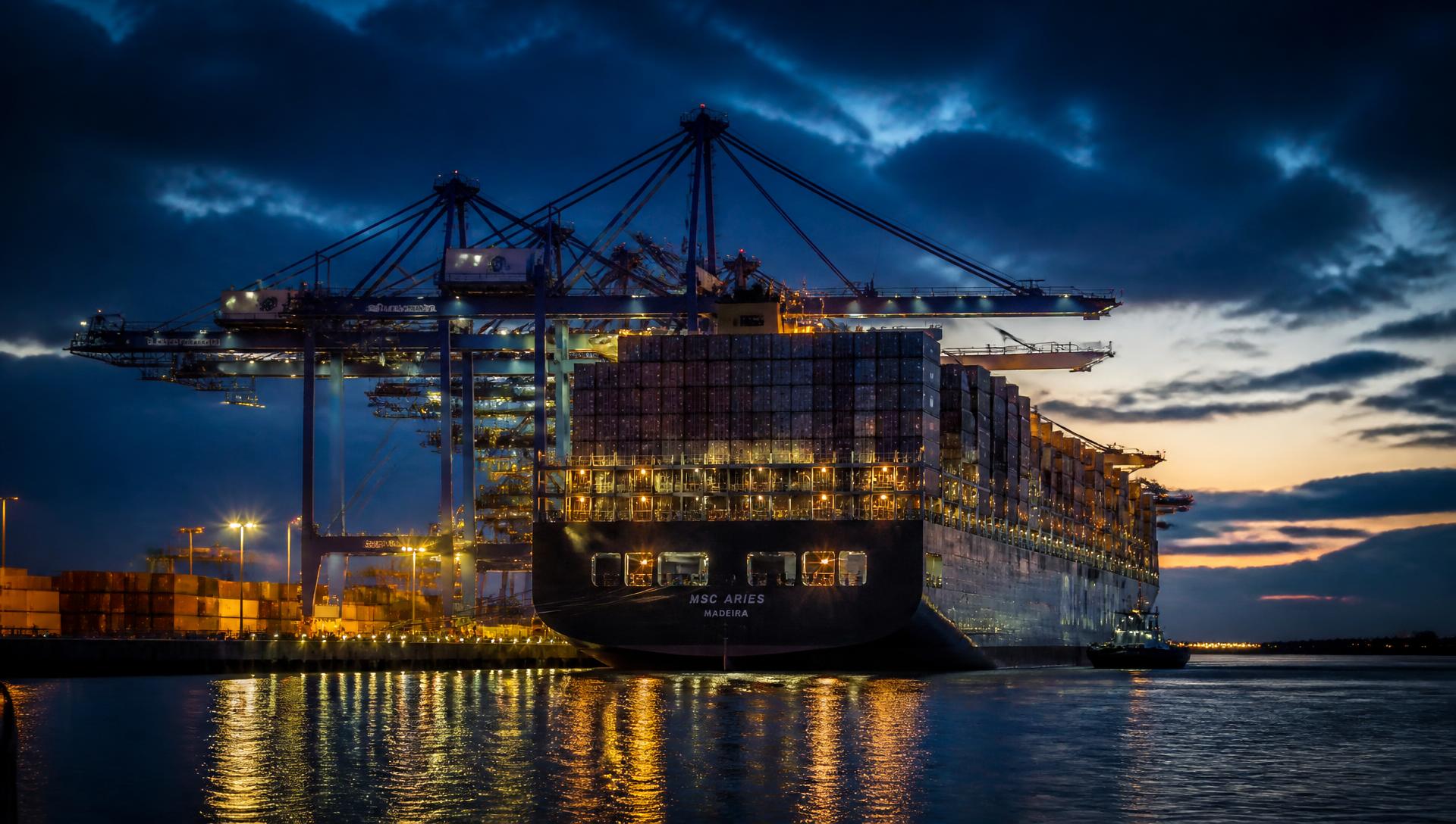 Container ship loading at a UK port at dusk